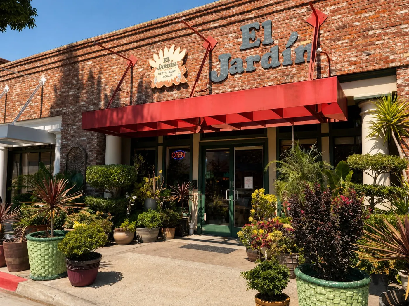 El Jardín's red awning and garden of potted plants out front